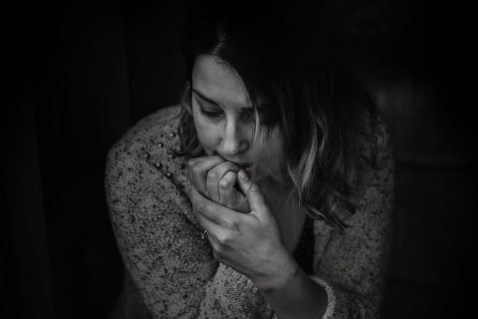 woman wearing long sleeved top, appearing depressed