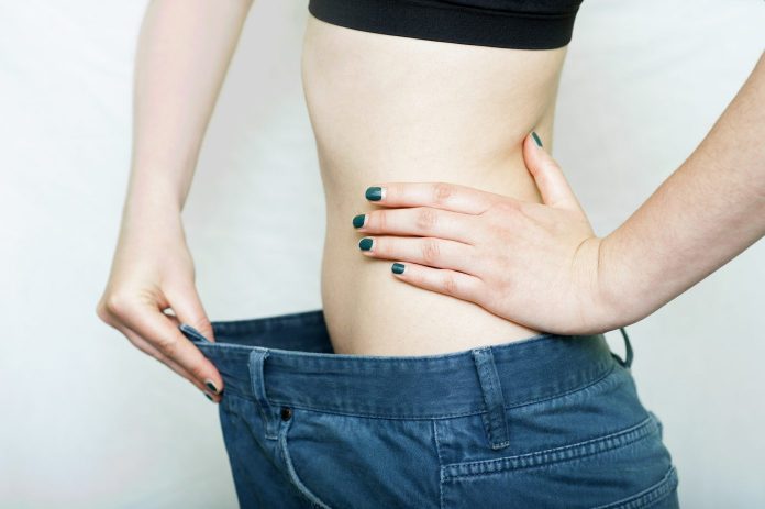 Slim woman wearing a big size pant showing it is too loose