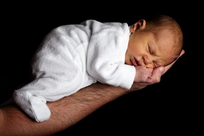 infant sleeping on hand