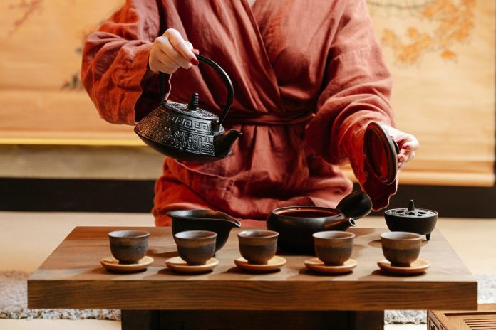 oriental lady pouring green tea in small cups