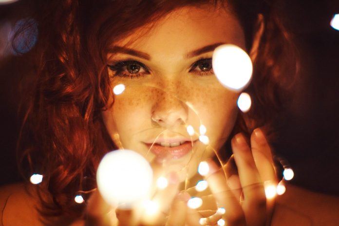 young woman in front of orange spots of light