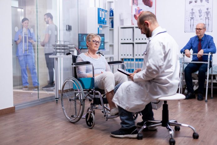 woman-with-parkinson-sitting-wheelchair-hospital-room-during-medical-examination