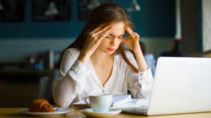 Nervous stressed female student feeling headache in a cafe