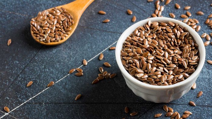flaxseed in a spoon and a bowel on a table