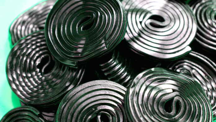 licorice sticks rolled on a peacock green background